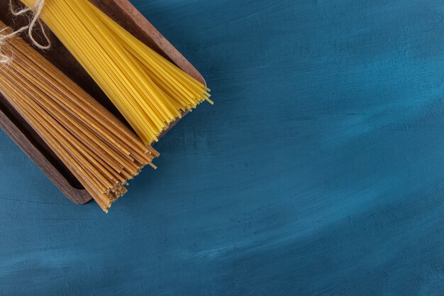 Top view of raw noodles on a dark-blue background . 