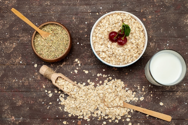 Top view raw oatmeal inside white plate on brown, with milk food raw health breakfast