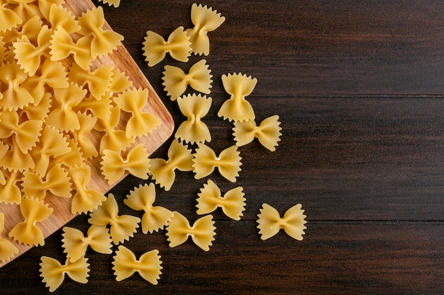 Top view of raw pasta on a cutting board on a wooden surface