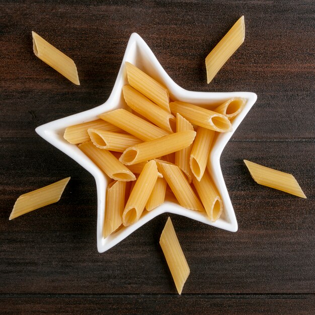 Top view of raw pasta in a star shaped rosette on a wooden surface