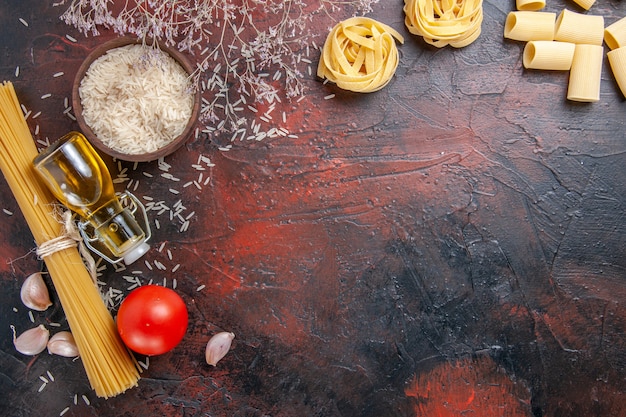 Foto gratuita vista dall'alto pasta cruda con diversi ingredienti sull'impasto per pasta di colore superficie scura