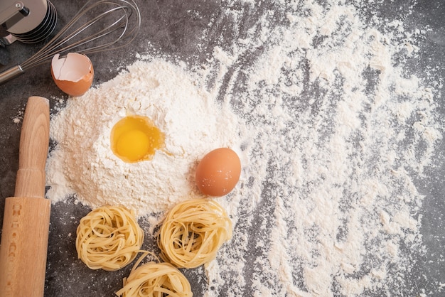 Top view raw pasta with egg in flour and copy-space