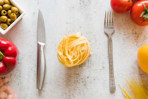 Foto gratuita vista dall'alto di pasta cruda con coltello e forchetta