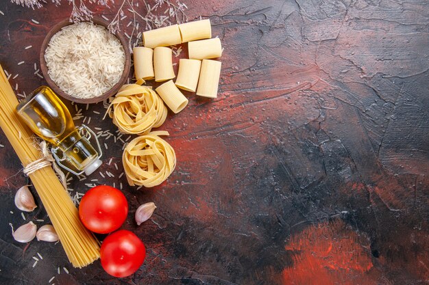 Foto gratuita vista dall'alto pasta cruda con riso e pomodori sulla pasta di pasta superficie scura cruda