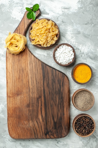 Pasta cruda vista dall'alto con condimenti su sfondo bianco