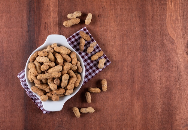 Top view raw peanuts in bowl on wooden  with copy space