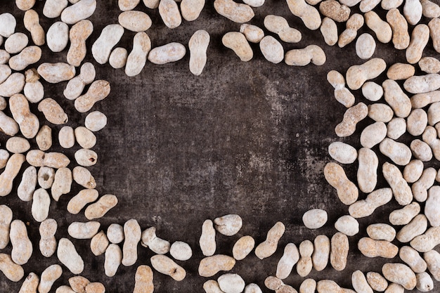 Free photo top view raw peanuts frame with copy space on stone  horizontal