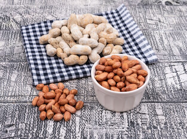 Top view raw peanuts on table cloth and in bowl on wooden  horizontal