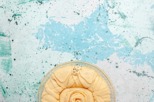 Вид сверху сырое тесто для пирога, круглое, сформированное на синей поверхности