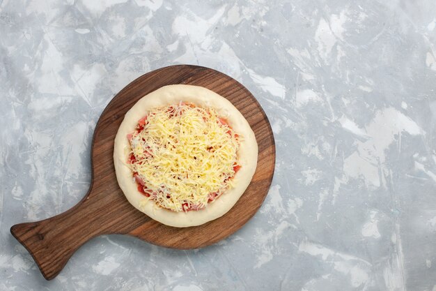 Top view raw pizza with cheese on white