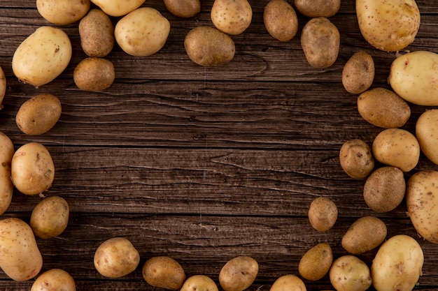 Top view raw potatoes with copy space on wooden background