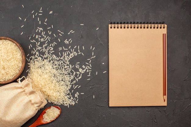 Free photo top view of raw rice inside bag and plate on a grey surface