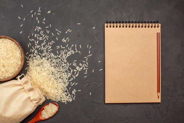 Top view of raw rice inside bag and plate on a grey surface