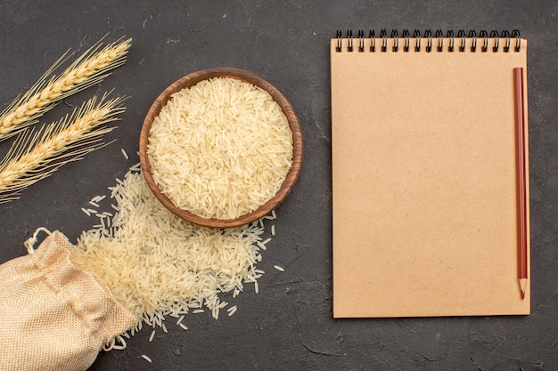 Top view of raw rice inside brown plate on a grey surface