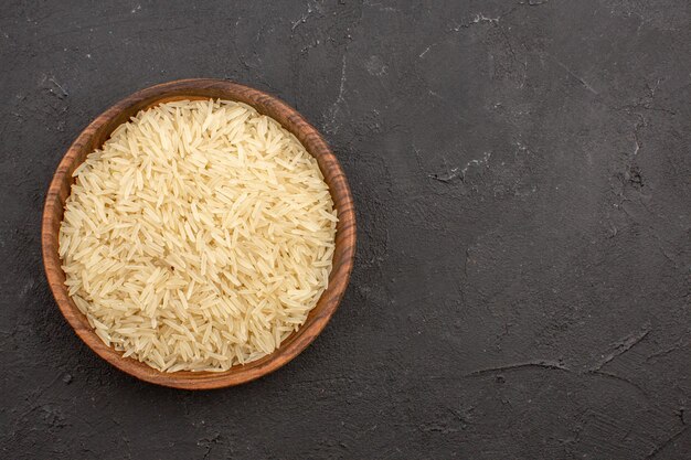 Top view of raw rice inside brown plate on a grey surface