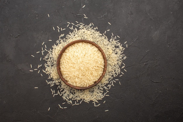 Top view of raw rice inside plate on dark grey surface