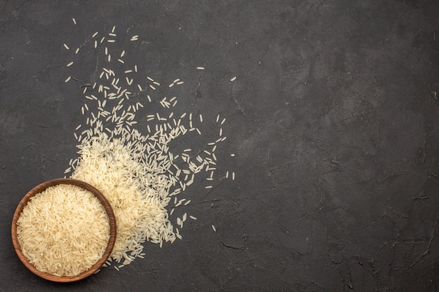 Free photo top view of raw rice inside wooden plate on grey surface