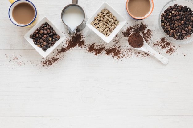 Top view of raw and roasted coffee beans with coffee cup on wooden table