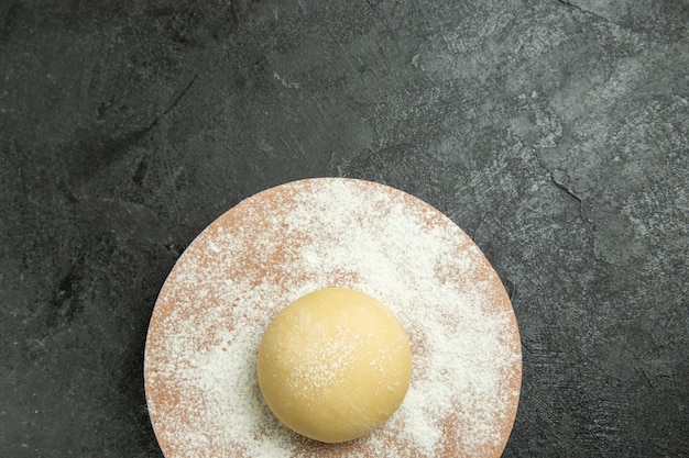 Top view raw round dough with flour on dark grey background dough meal flour food raw