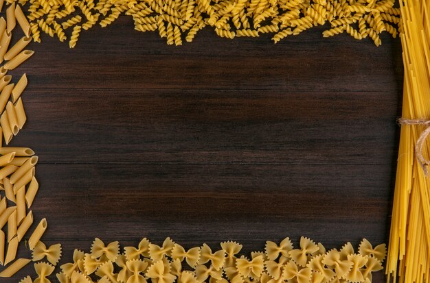 Top view of raw spaghetti with pasta on wooden surface