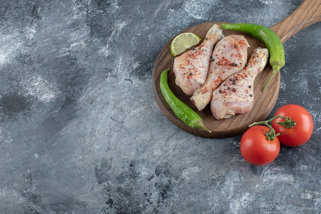 Top. view. Raw spicy chicken drumsticks with green pepper and tomatoes.