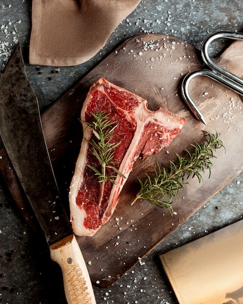 Top view of raw t-bone steak garnished with rosemarine