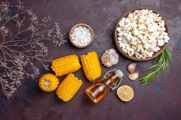 Top view raw yellow corns with fresh popcorn on dark surface snack popcorn movies plant corn