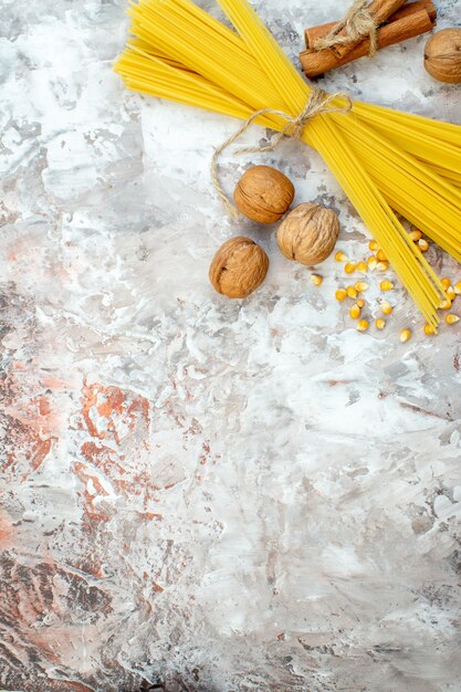 Top view raw yellow pasta with walnuts on light surface