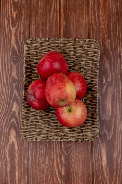 Top view of red apples in basket plate on wooden table