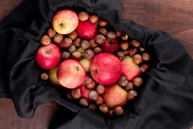 Вид сверху красные яблоки с орехами в черном ящике на коричневой деревянной горизонтальной