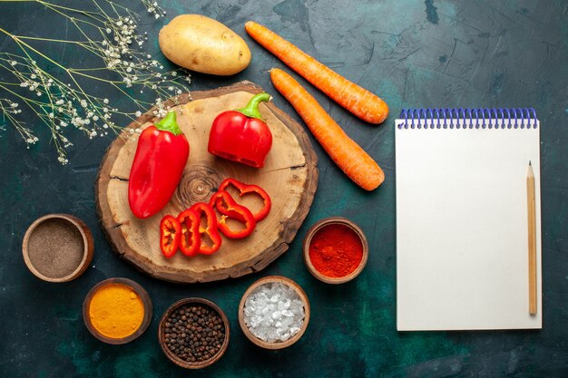 Top view red bell-pepper with different seasonings on dark-green desk vegetable spicy hot food