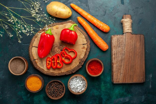 Top view red bell-pepper with different seasonings on dark-green surface vegetables spicy hot food