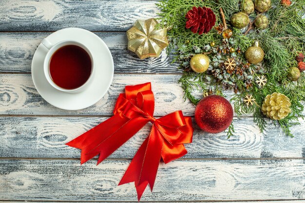 Top view red bow a cup of tea fir tree branches on wooden surface