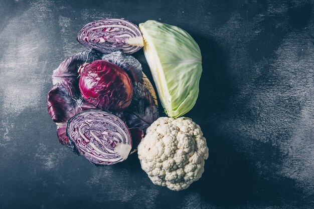 Top view red cabbage with cauliflower, sliced cabbage on dark textured background. horizontal