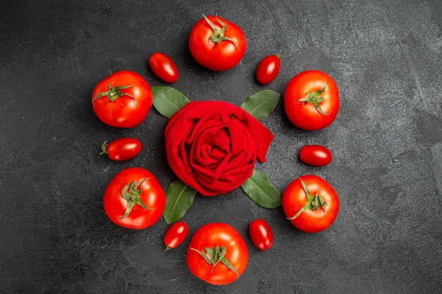 장미 모양의 수건 주위의 상위 뷰 빨간색과 체리 토마토와 복사 공간이 어두운 땅에 베이 잎