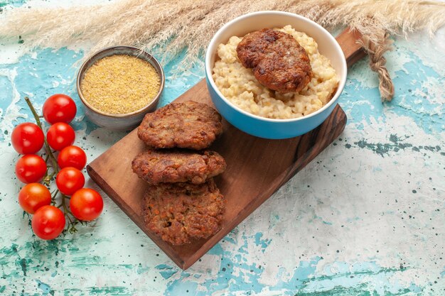 Top view red cherry tomatoes with meat cutlets on blue desk