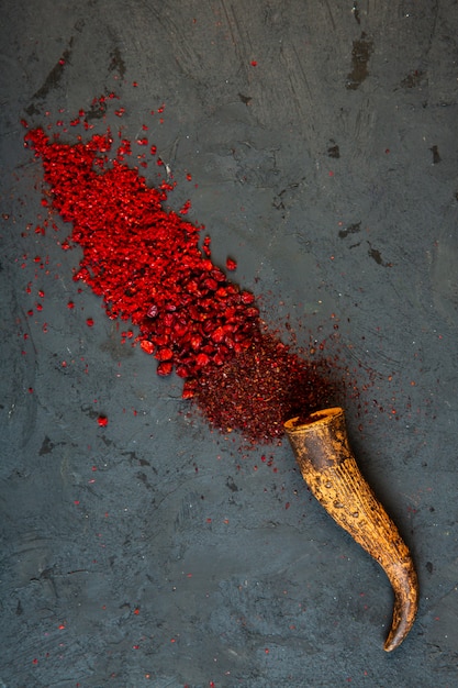 Foto gratuita vista dall'alto di peperoncino rosso e spezie in polvere di sumac sparse da un corno sul nero