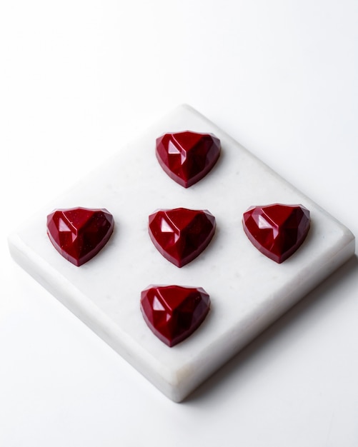 Top view red chocolate heart shaped sweets on white stand