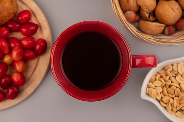 Вид сверху красной чашки кофе с сердоликом на деревянной кухонной доске с орехами на ведре на серой стене