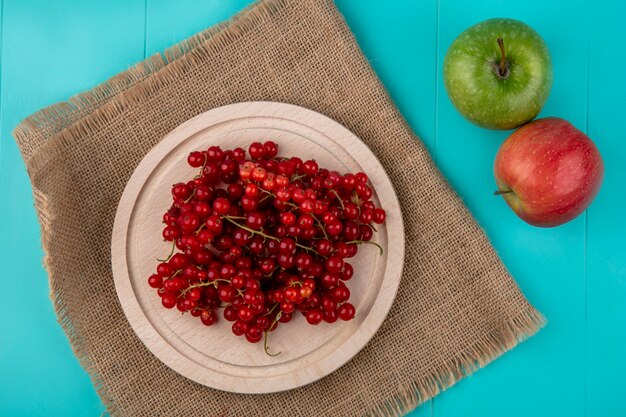 Top view red currant on a plate with apples on a light blue background