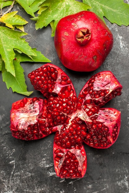 Free photo top view red fresh pomegranate with green leaves on dark surface