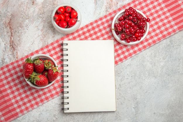 Top view red fruits with berries on white table fresh fruit berry notepad