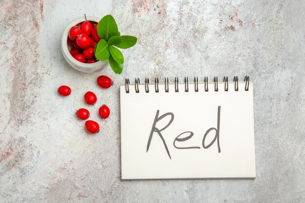 Top view red fruits with red written notepad on white table berry red fruit