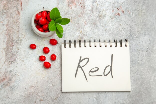 白いテーブルベリー赤い果物に赤い書かれたメモ帳と上面図赤い果物