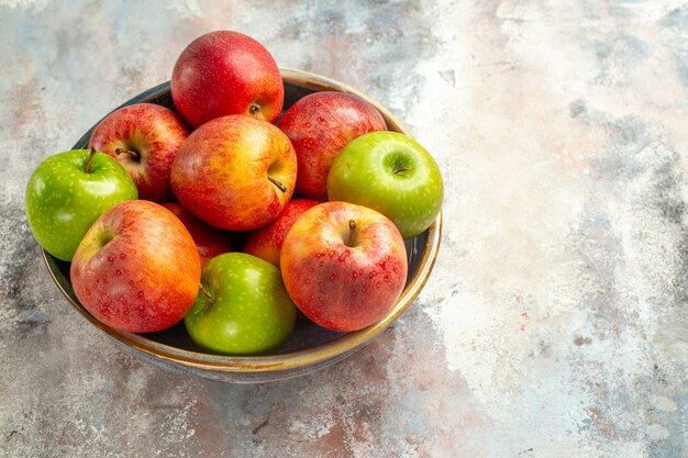 Top view red and green apples in bowl on nude surface copy space