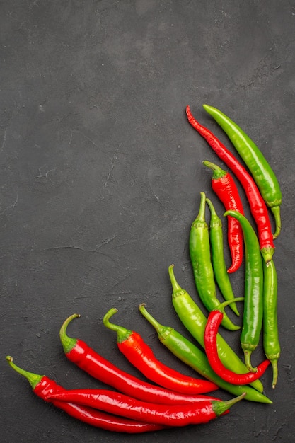 Top view red and green peppers at the right side of black table with free space