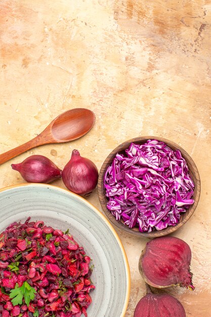 Top view red healthy salad mixed with parsley leaves made of beetroots and bowl of chopped cabbage on a wooden background with copy place
