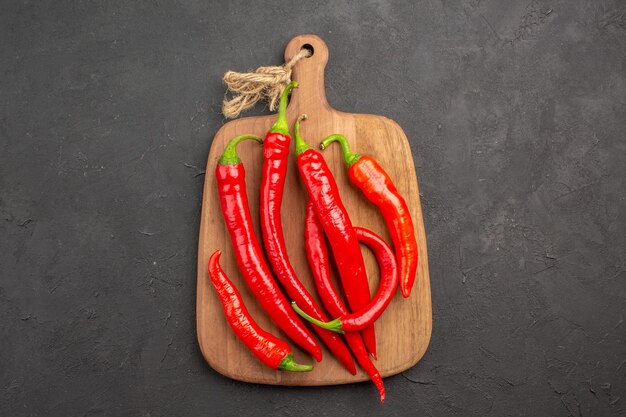 Top view red hot peppers on a chopping board at the center of the black table with copy space