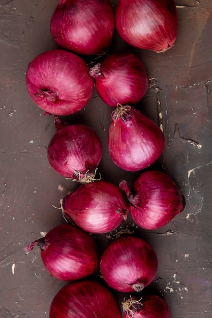 Free photo top view of red onions on maroon background