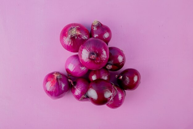 Top view of red onions on purple background with copy space 1